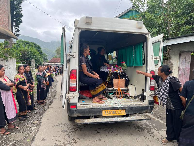 Residents of Motbung line up to pay their tributes, as a funeral procession passes by